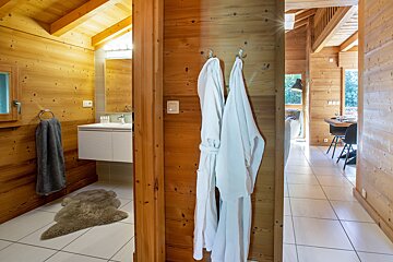 A bathroom in a wooden cabin with robes hanging on hooks
