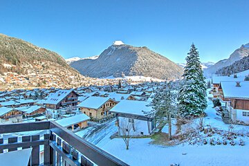 A view of a snowy village with mountains in the background