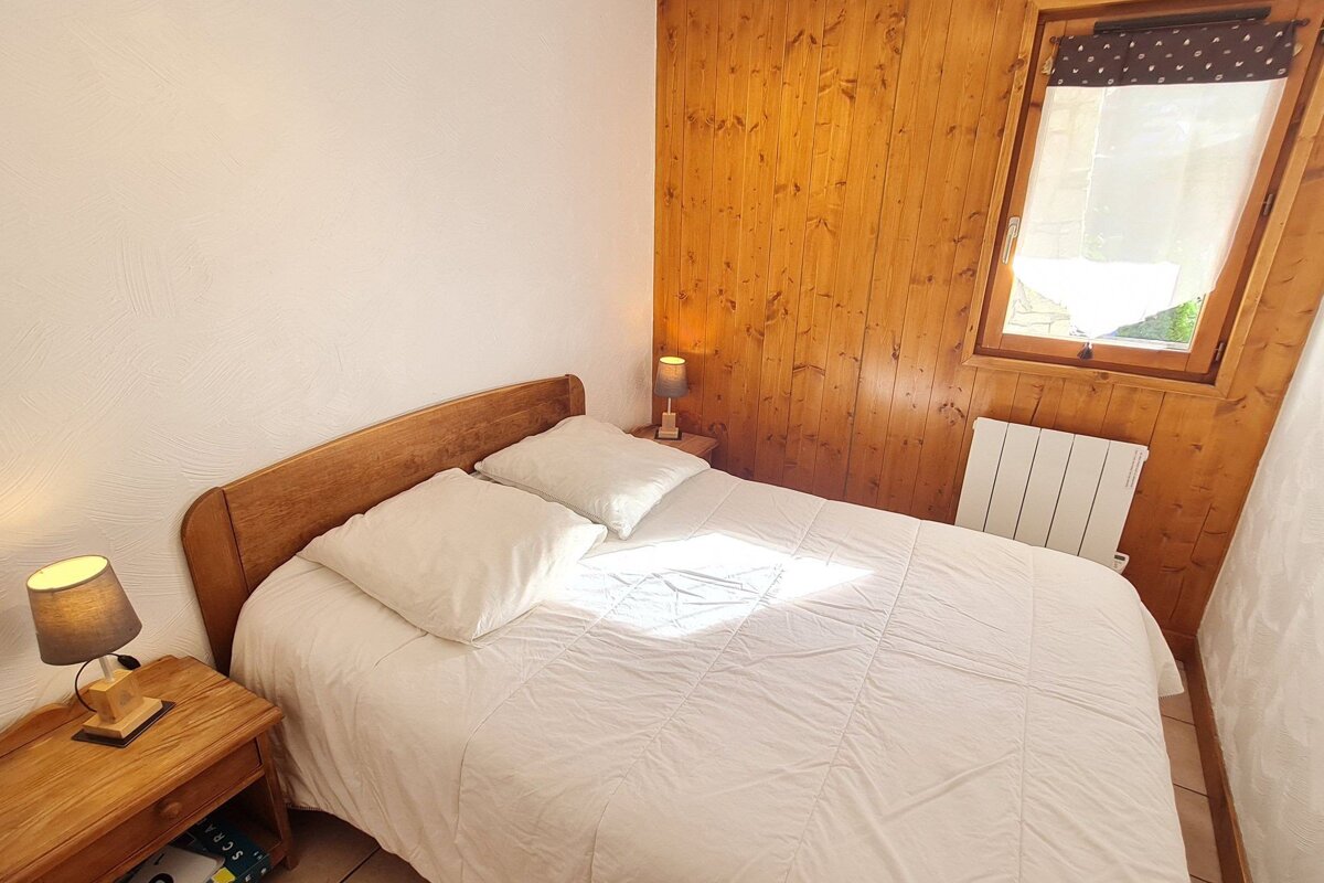 A small bedroom with a bed and two lamps