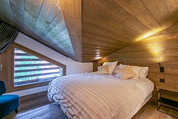 A bedroom with a bed and a chair in it