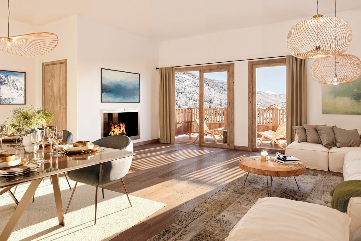 Cozy living-dining room with a fireplace, wooden floors, and balconies opening to snowy mountain views.
