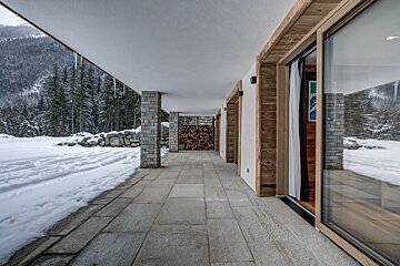 A patio with snow on the ground and trees in the background