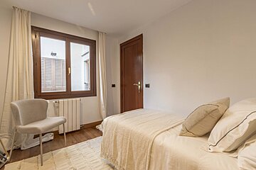 A bedroom with a bed a chair and a window