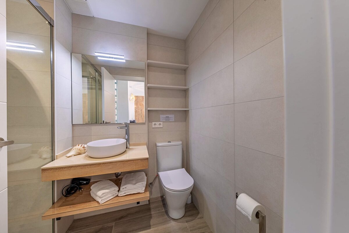 A bathroom with a toilet a sink and a mirror