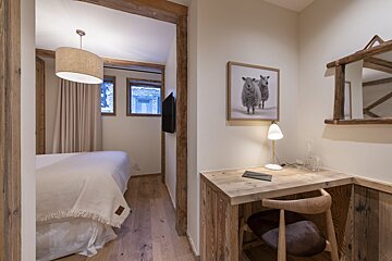A bedroom with a desk and a picture of two sheep on the wall