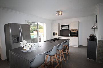 A kitchen with a large island and a stainless steel refrigerator