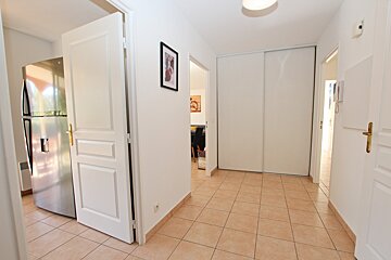 A hallway with a refrigerator and a picture on the wall