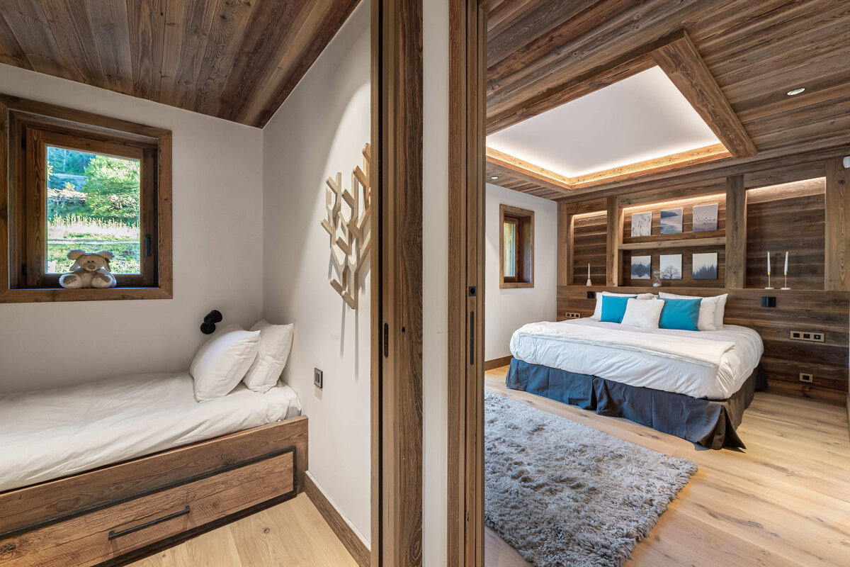 A bedroom with a bed and a teddy bear on the window sill