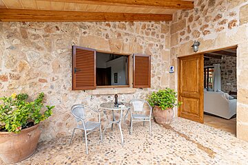 A patio with a table and chairs in front of a stone wall