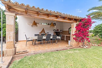 A patio with a table and chairs under a wooden roof