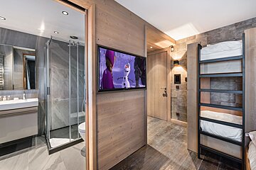A bathroom with a television on the wall that shows frozen