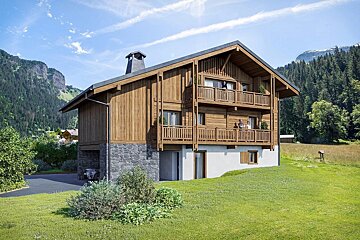 A modern wooden chalet with people on balconies, integrated garage with car, set in a sunny, green mountain landscape.