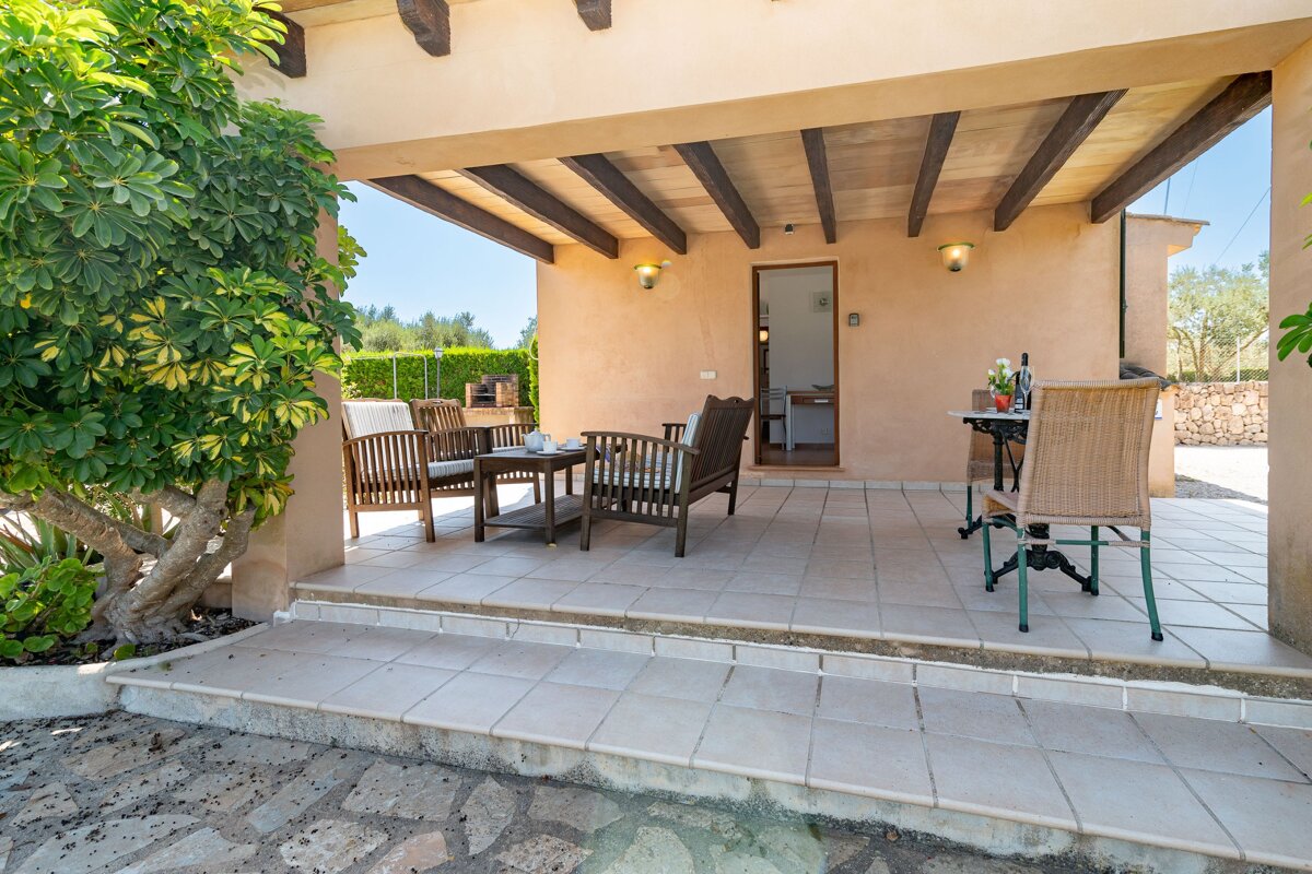A patio with a table and chairs under a wooden roof