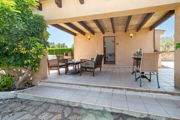 A patio with a table and chairs under a wooden roof