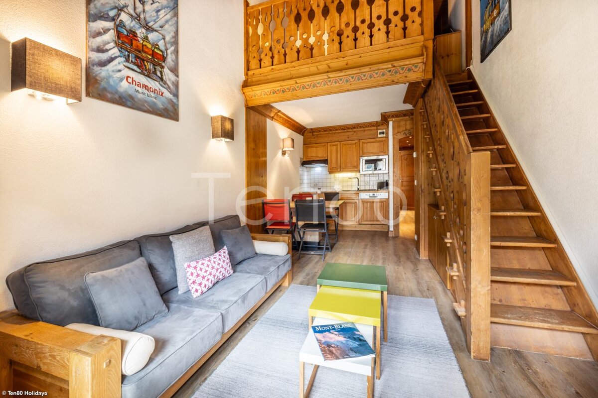 A living room with a couch and stairs and a poster on the wall that says chamonix