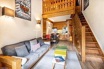 A living room with a couch and stairs and a poster on the wall that says chamonix