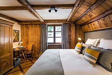 A bedroom with wood paneling and a large bed