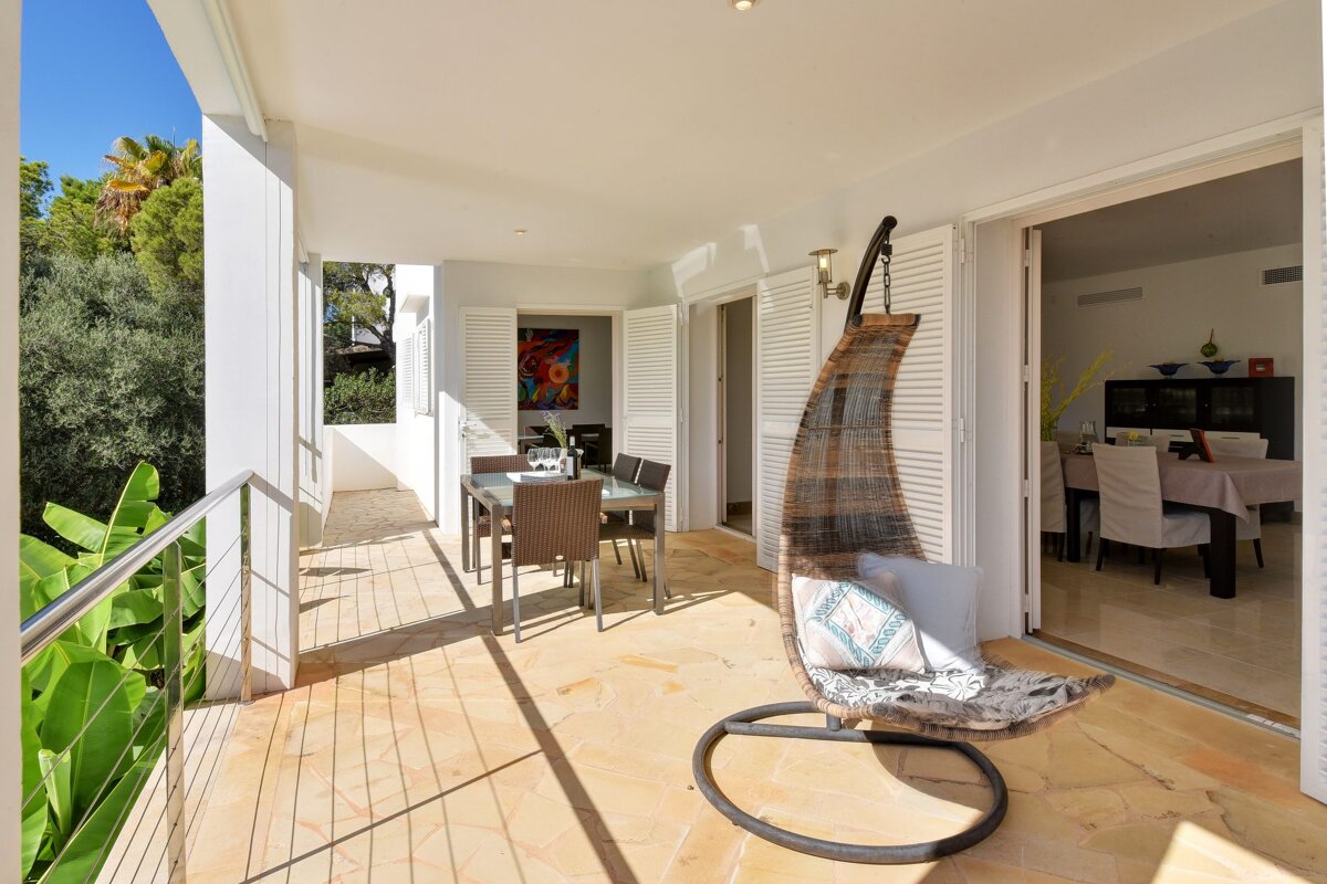 A balcony with a hanging chair and a table and chairs