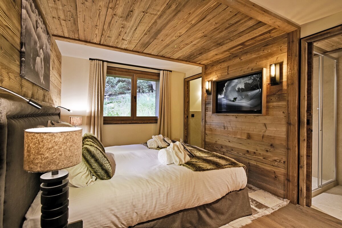 A bedroom with a bed and a television on the wall