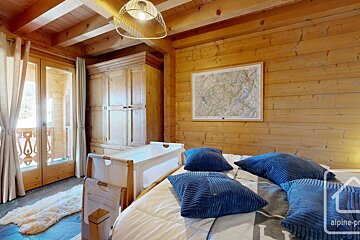 A wooden bedroom with a crib and a map on the wall