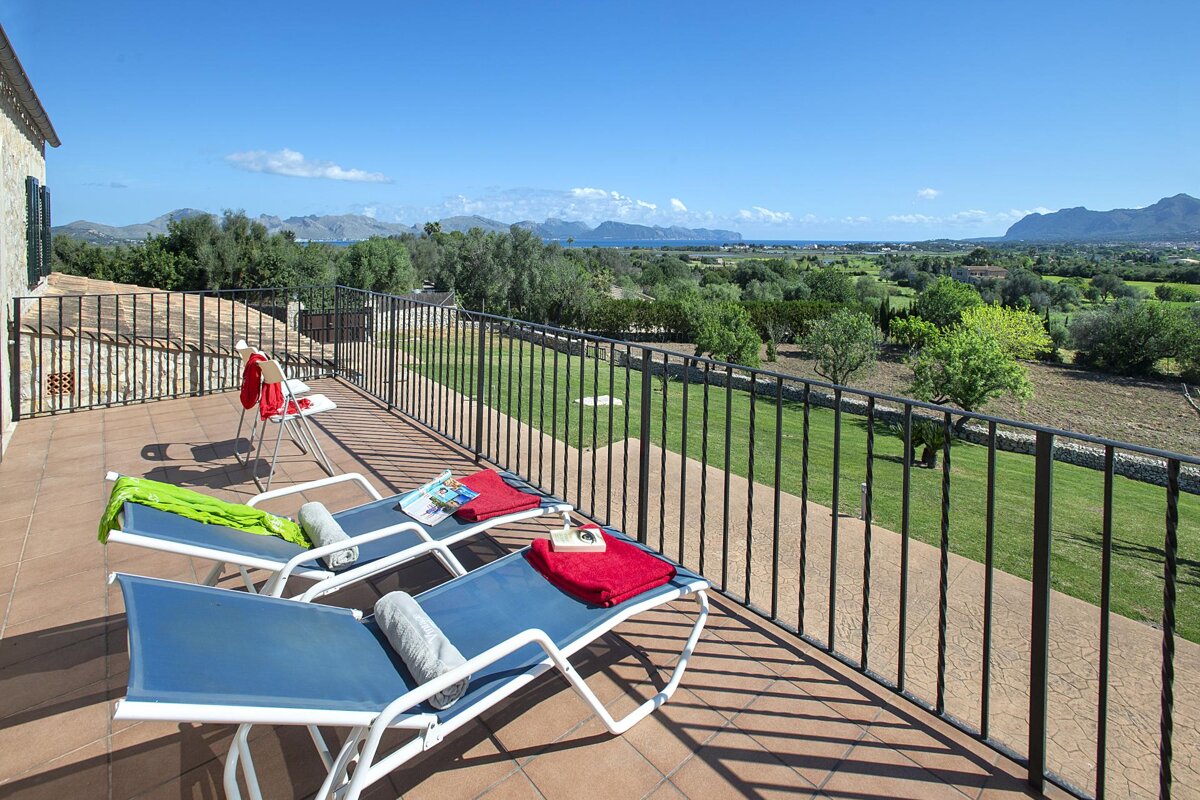 Two lounge chairs on a balcony with mountains in the background
