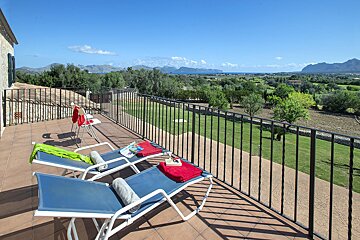 Two lounge chairs on a balcony with mountains in the background