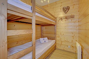 A bunk bed in a wooden cabin with a heart on the wall above it
