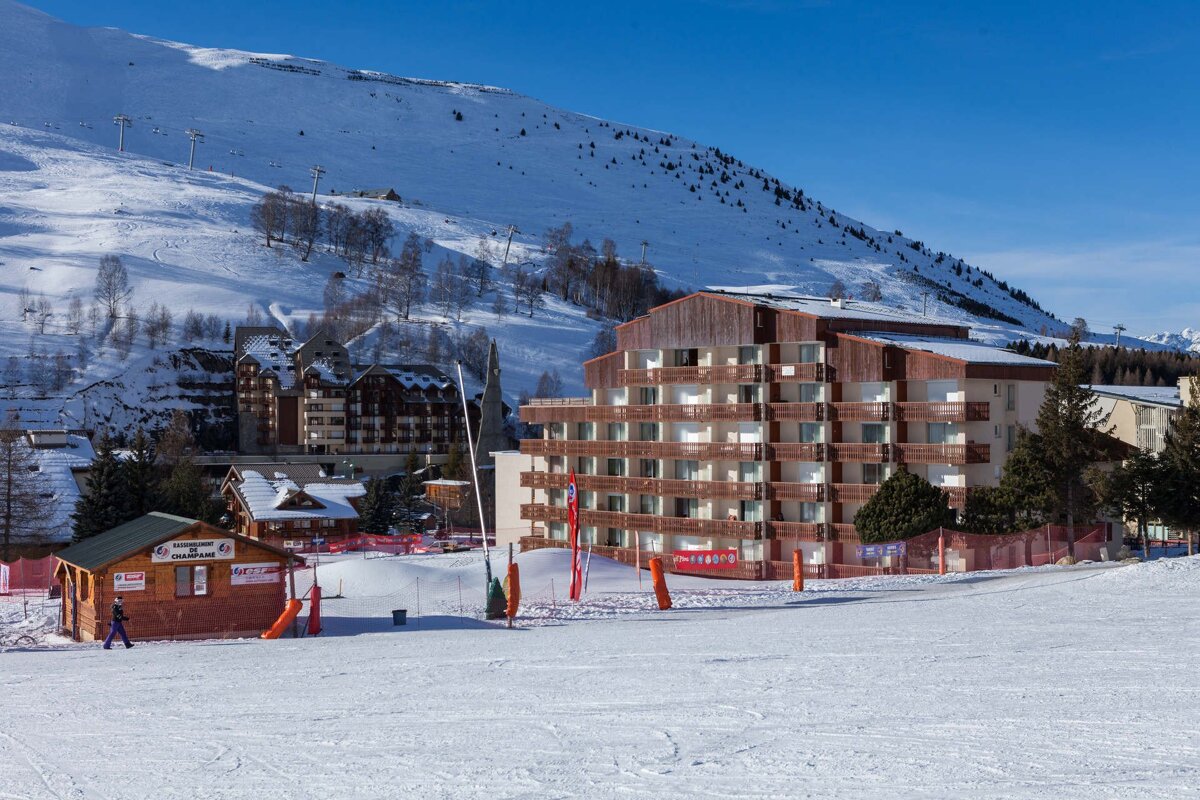 A ski slope with a building in the background that says ' hotel ' on it