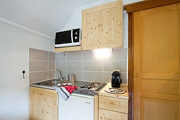A small kitchen with a miele dishwasher and a microwave