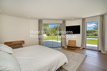 A bedroom with a large bed and a flat screen tv made in janssens provence immobilier