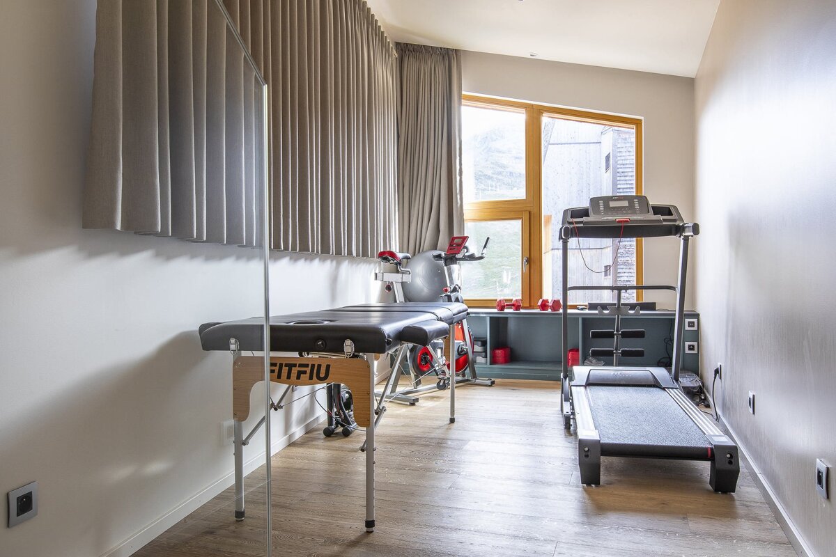 A room with a treadmill and a table that says fitfiu