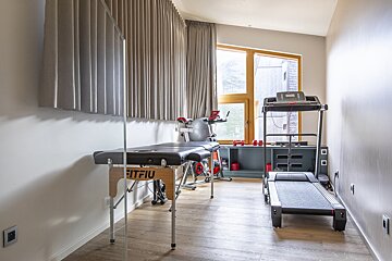 A room with a treadmill and a table that says fitfiu