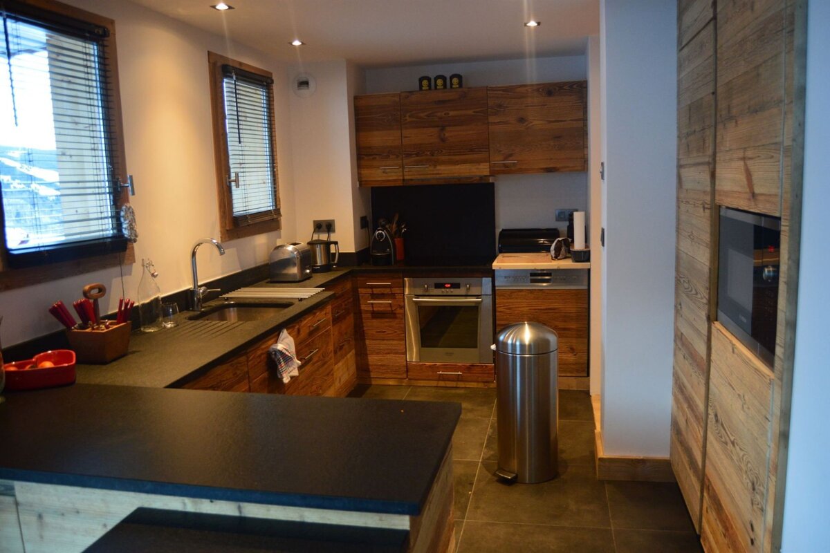 A kitchen with wooden cabinets and a stainless steel trash can