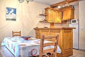 Cozy dining and kitchen area featuring wooden cabinets, a bar counter, a white refrigerator, and a table set with a patterned tablecloth.