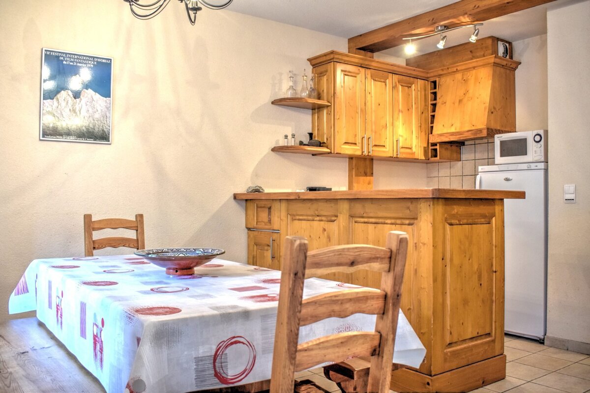 Cozy kitchen and dining area with light wood cabinets, a dining table with a patterned cloth, and chairs. Appliances are visible.
