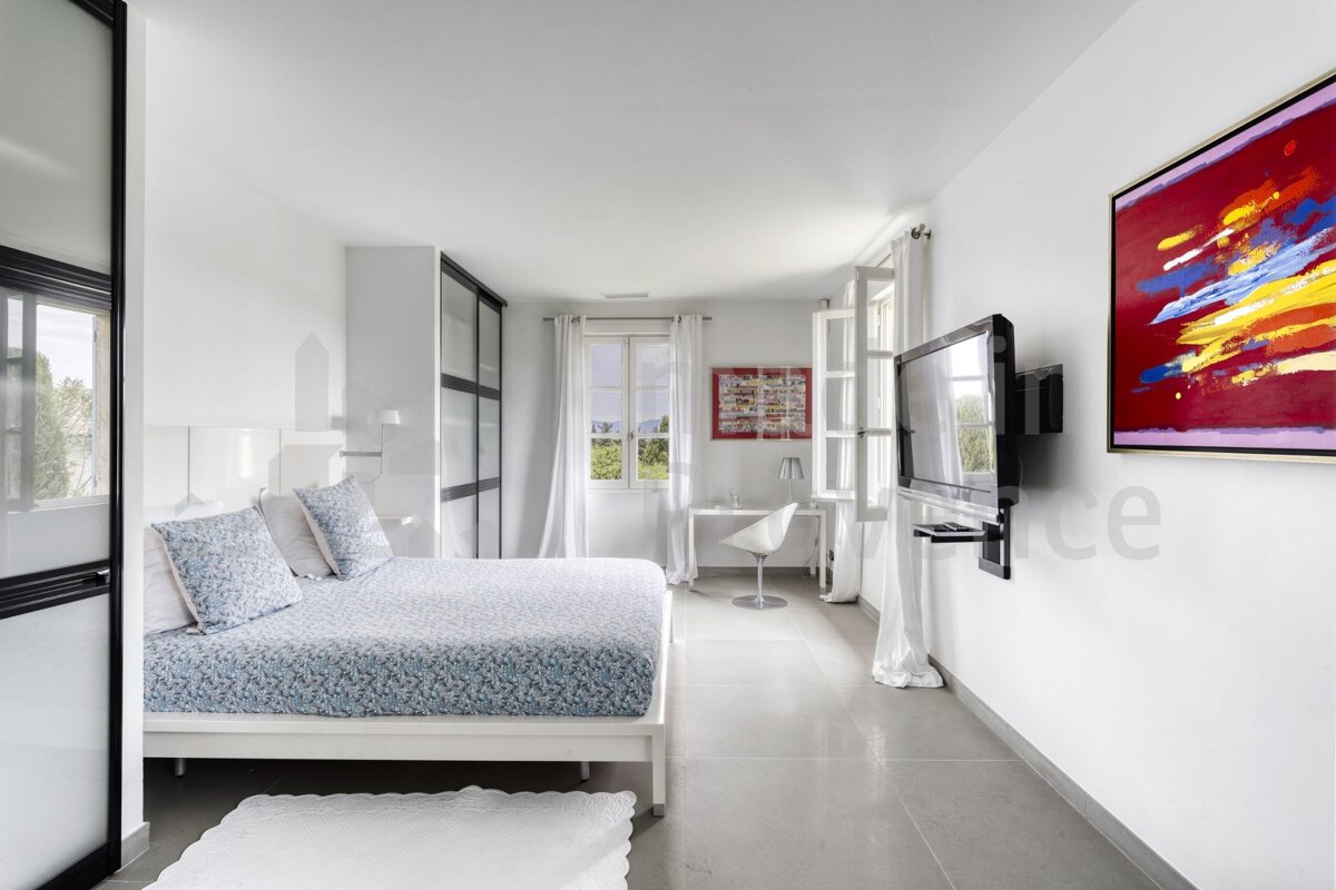 A bedroom with a large painting on the wall above the bed
