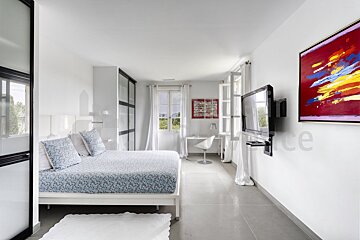 A bedroom with a large painting on the wall above the bed