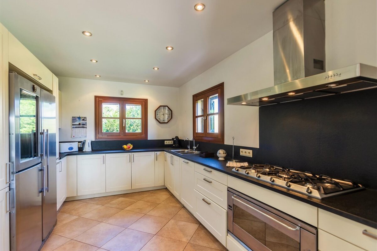 A kitchen with a stove top oven and a clock on the wall