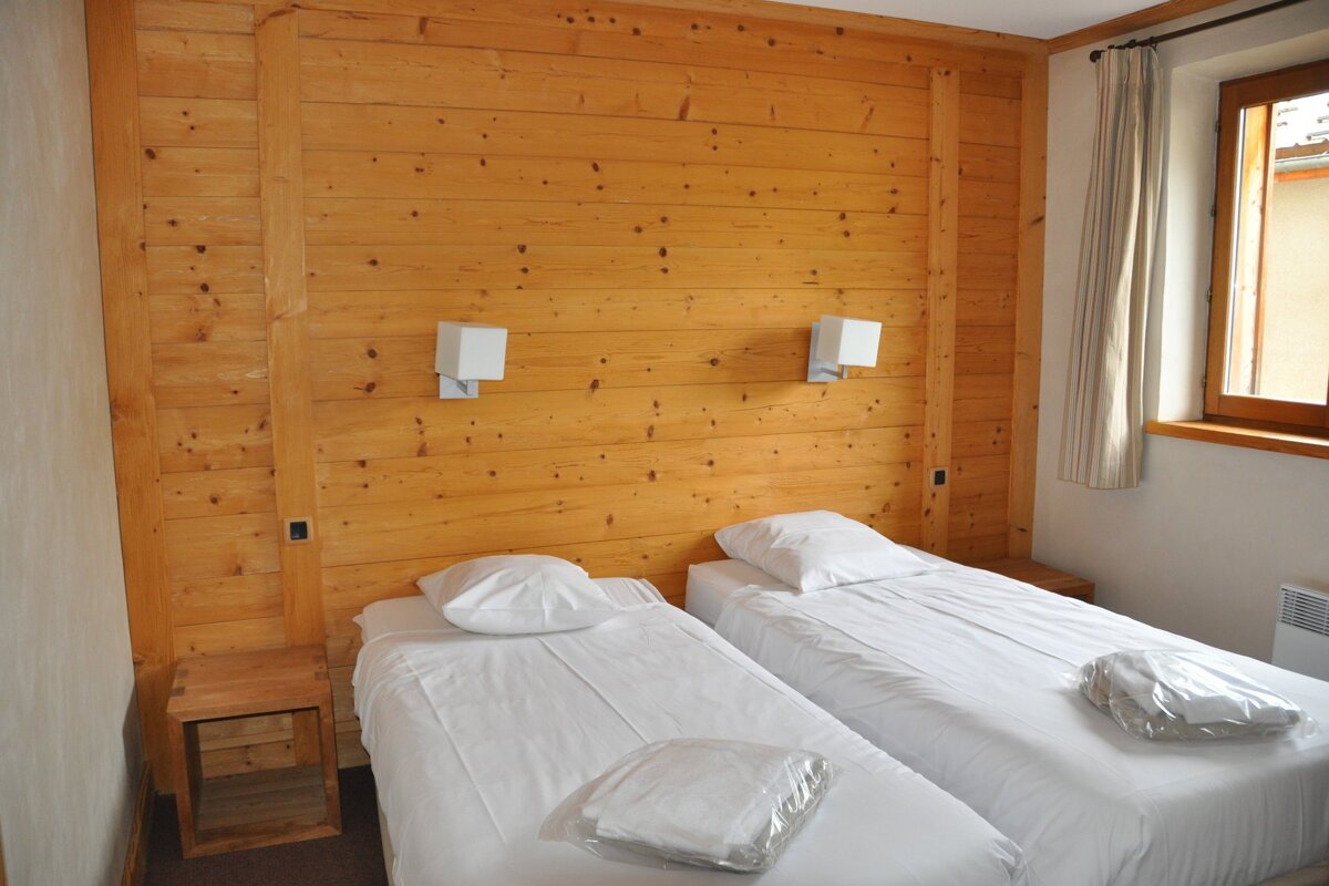 A bedroom with two beds and a wooden wall