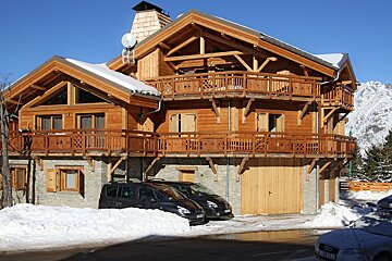 A black audi is parked in front of a large wooden house