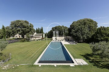 A large swimming pool in the middle of a lush green field