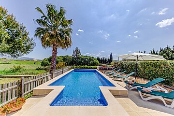 A large swimming pool surrounded by chairs and an umbrella