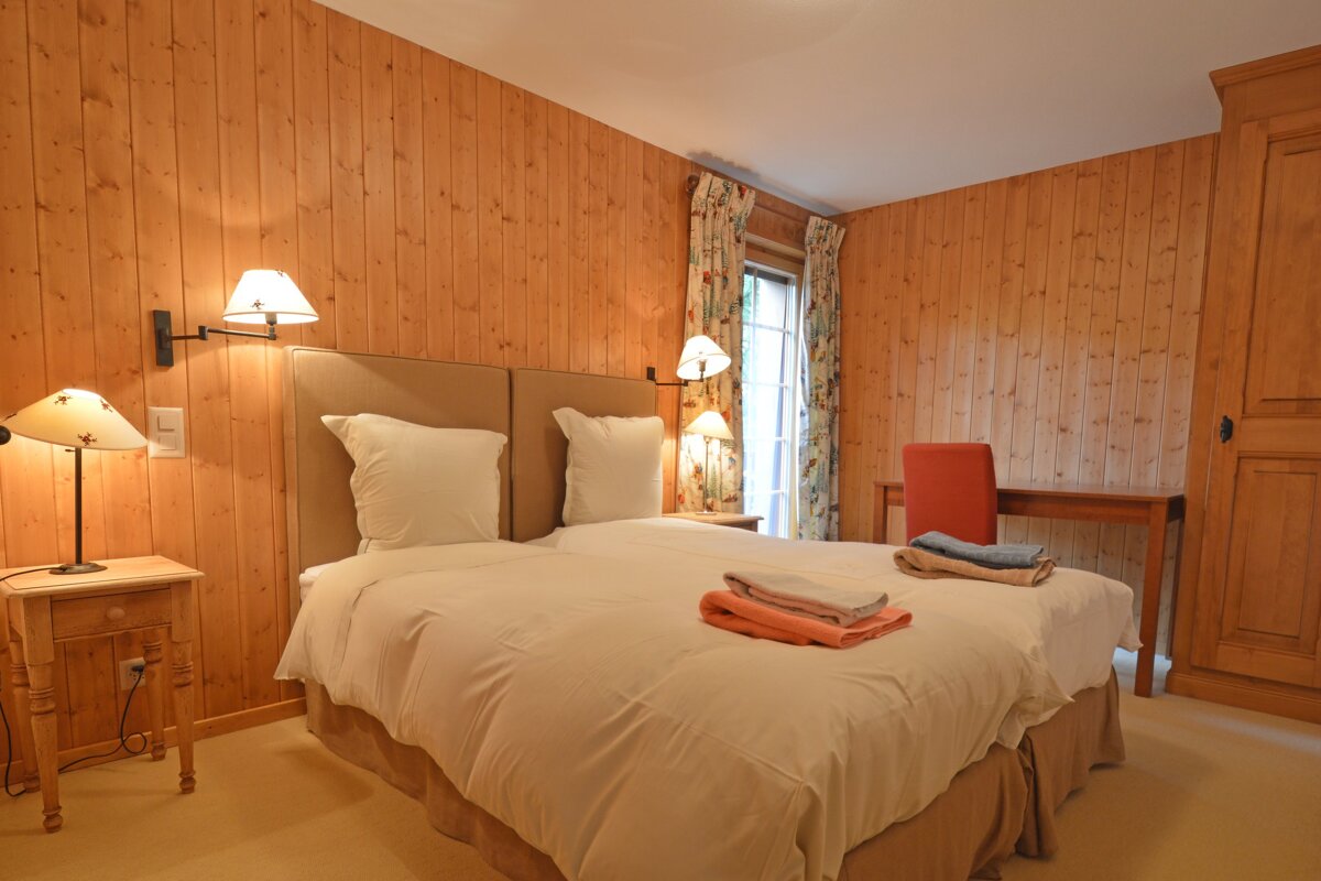 A bedroom with wood paneled walls and two beds