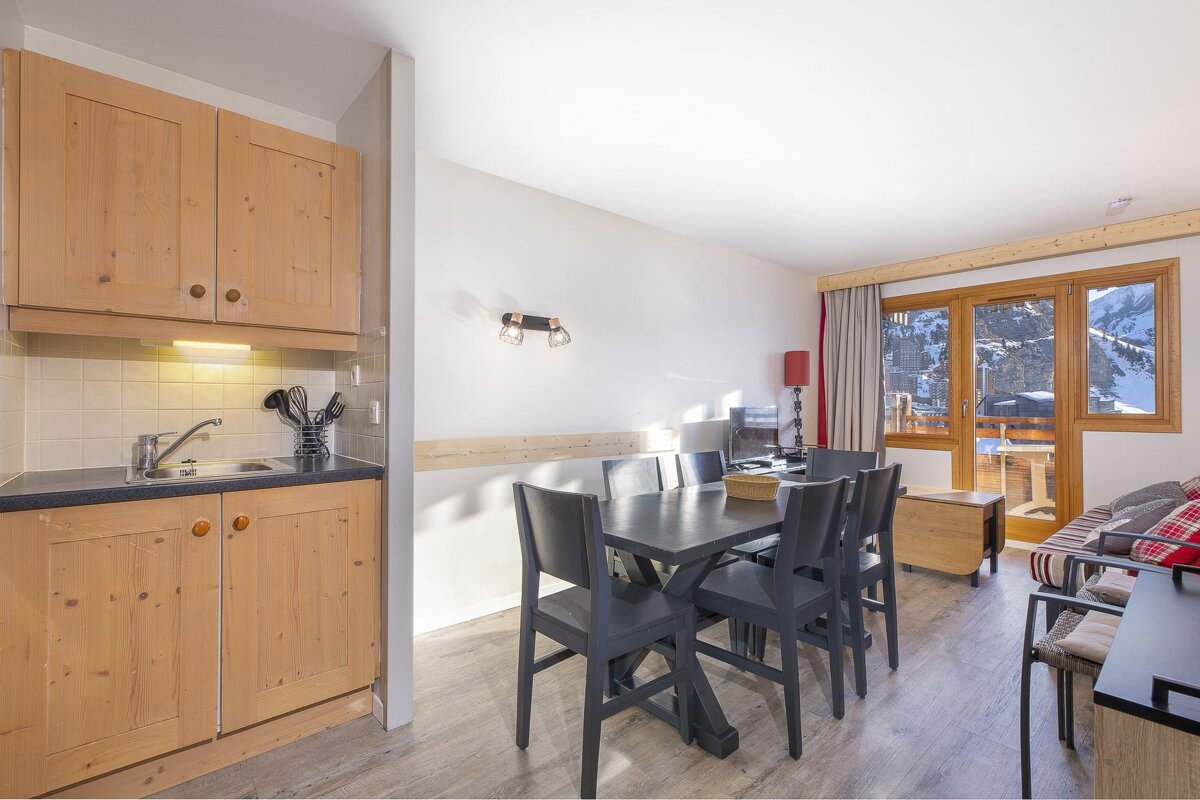 A kitchen with a sink and a table and chairs