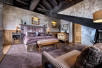 A bedroom with a large bed and a chair
