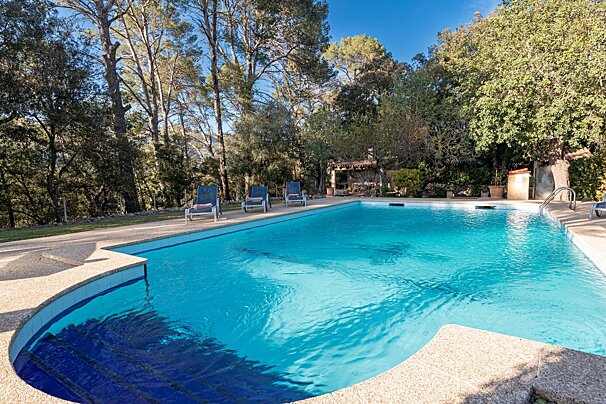 A large swimming pool surrounded by chairs and trees