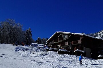 A snowy ski slope with a building in the background