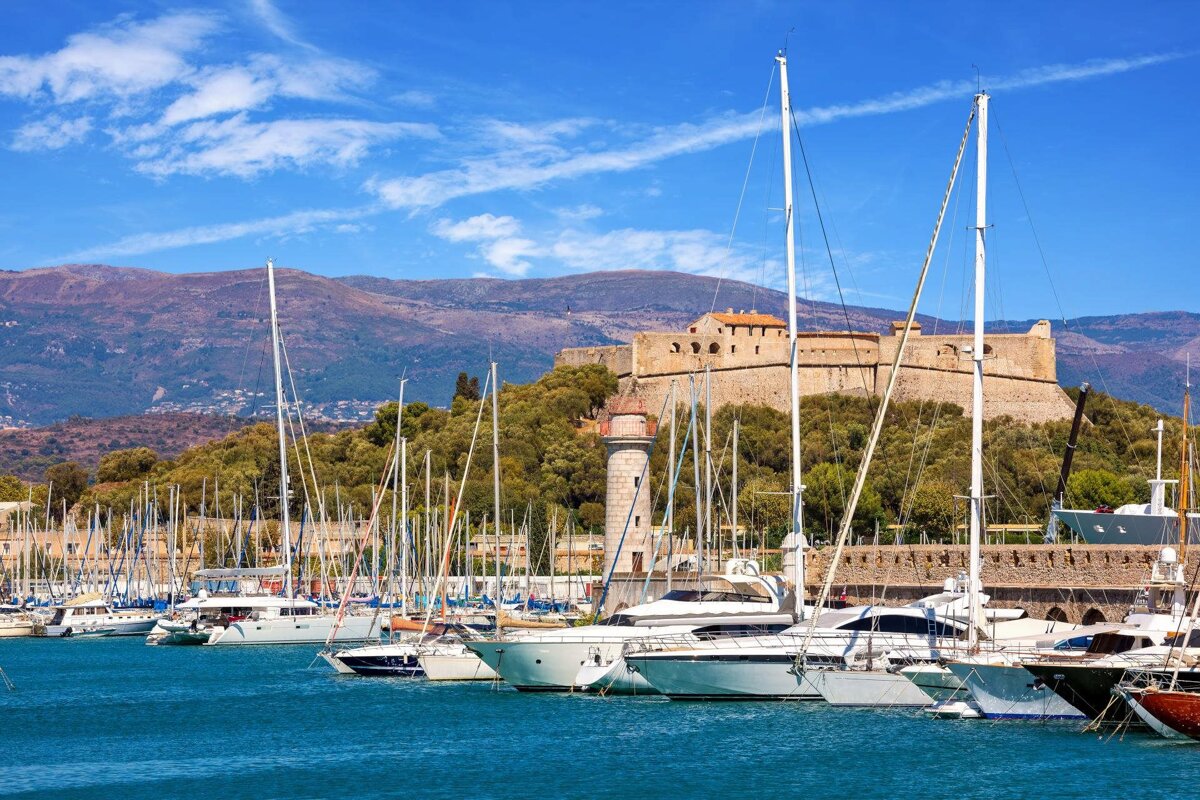 Boats are docked in a harbor with mountains in the background