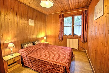 A wooden bedroom with a bed and two lamps