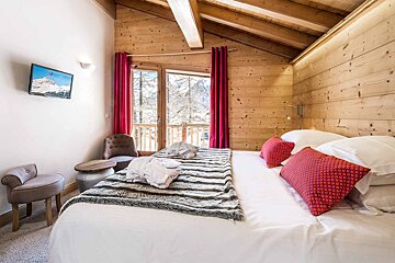 A bedroom with a large bed and a television on the wall